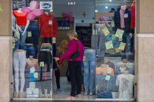 Cliente aponta peça de roupa em vitrine de loja